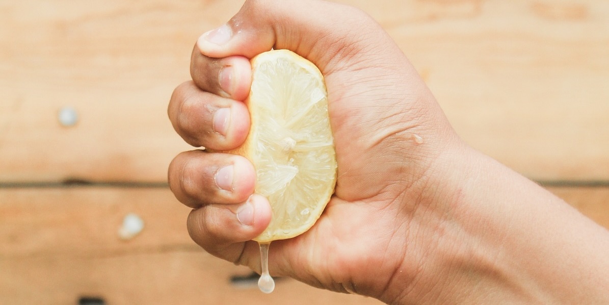 Eine Hand, die eine aufgeschnittene Zitrone ausdrückt